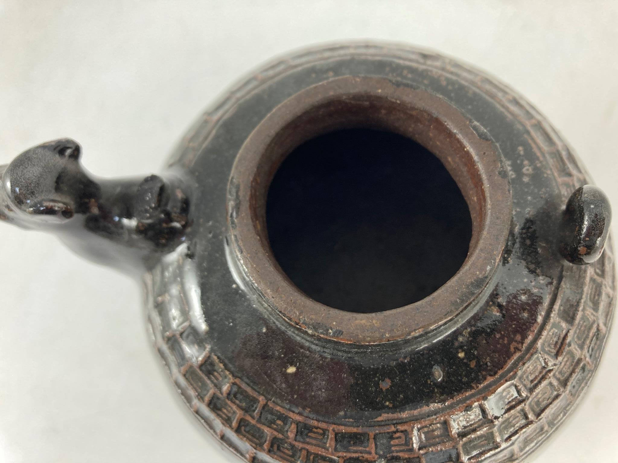 An unusual Chinese black ware tenmoku glazed tripod wine pot, 19th/20th century, with camel head spout, zoomorphic feet, 14cm high, hongmu stand